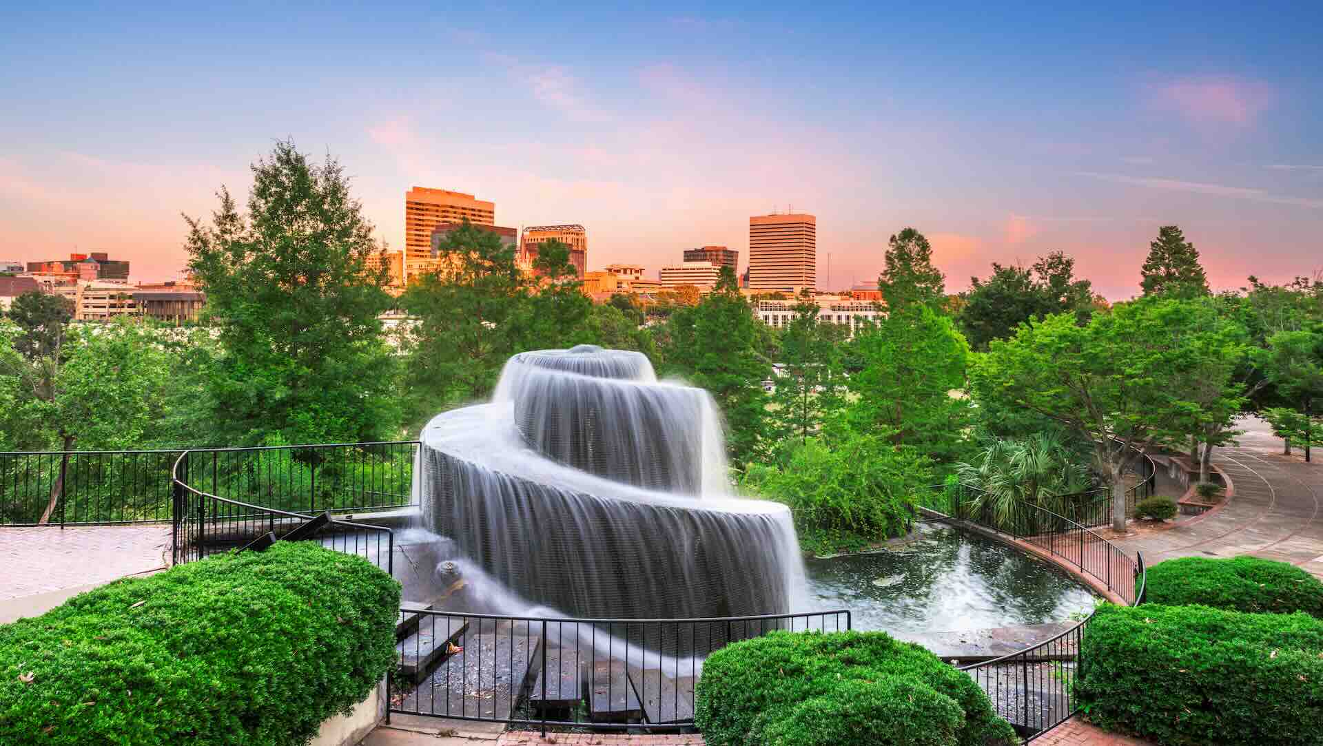 Cascading waterfall in a city park at sunset.