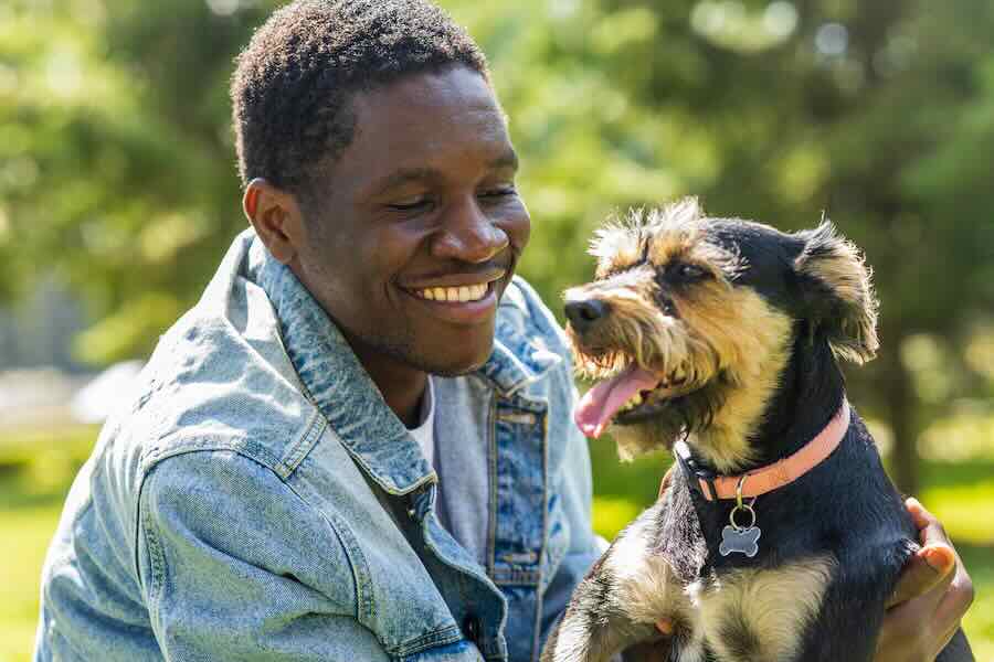 Smiling man with a playful dog outdoors.